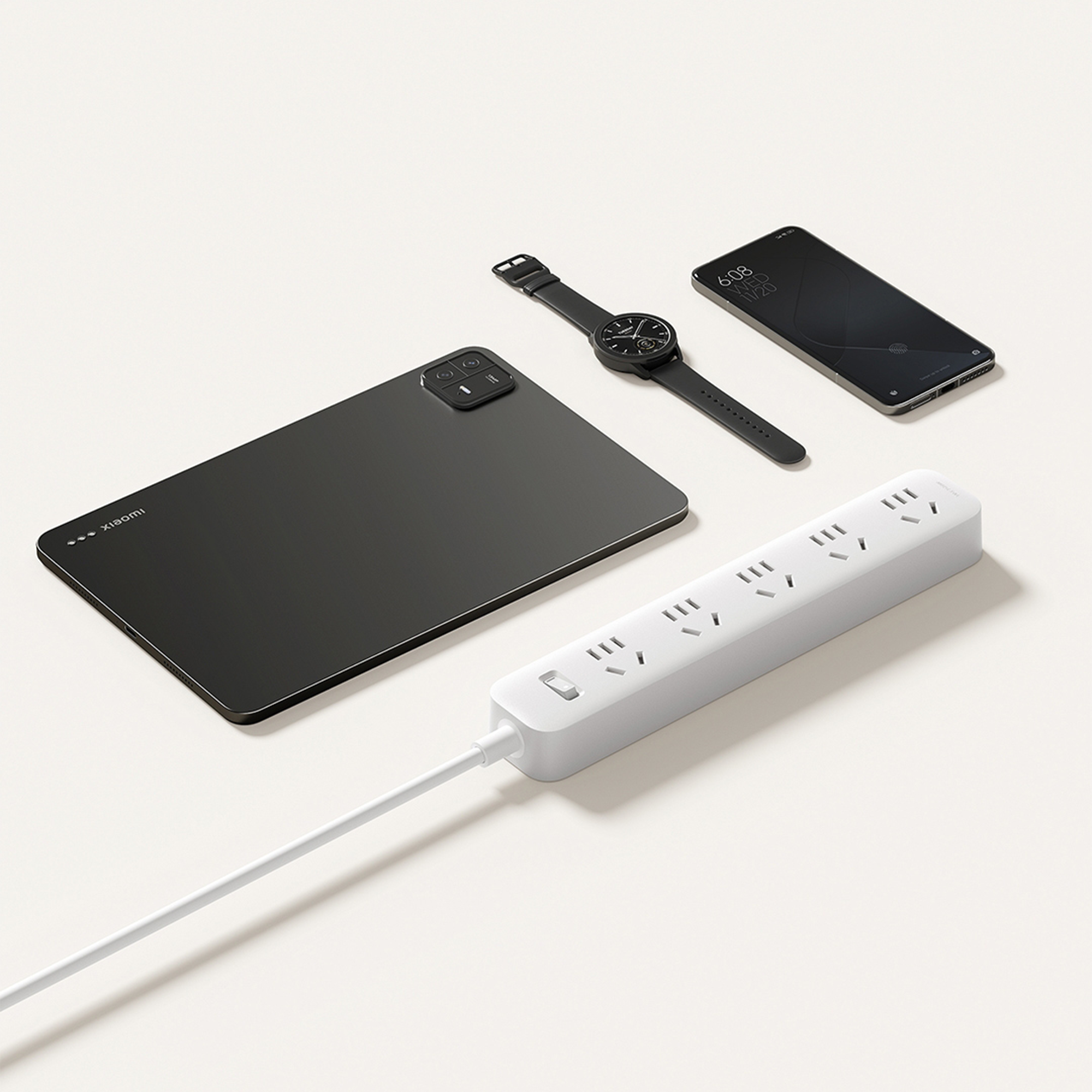 White Xiaomi power strip with multiple outlets and a power switch, surrounded by Xiaomi tablet, phone, and smartwatch.
