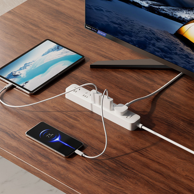 White Xiaomi power strip with multiple outlets charging tablet & smartphone on brown wooden desk.