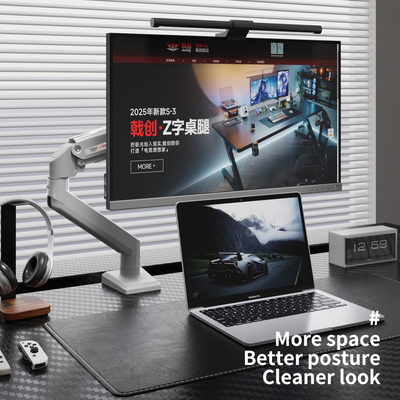 Black M1 monitor arm mounted on desk holding a widescreen monitor above a laptop with an ergonomic workspace setup