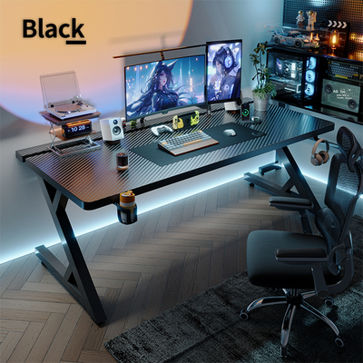 Black carbon fiber S3 gaming desk with blue LED underglow, dual monitors, gaming PC, and black ergonomic chair.