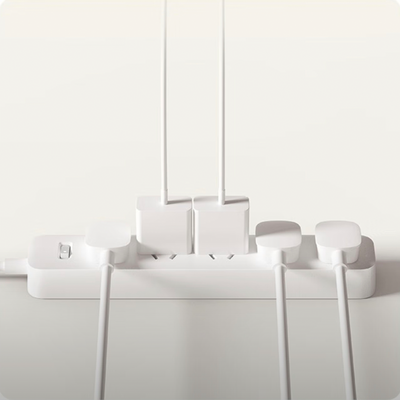 White Xiaomi power strip with 6 outlets, a power switch, and four white chargers with cables plugged in.
